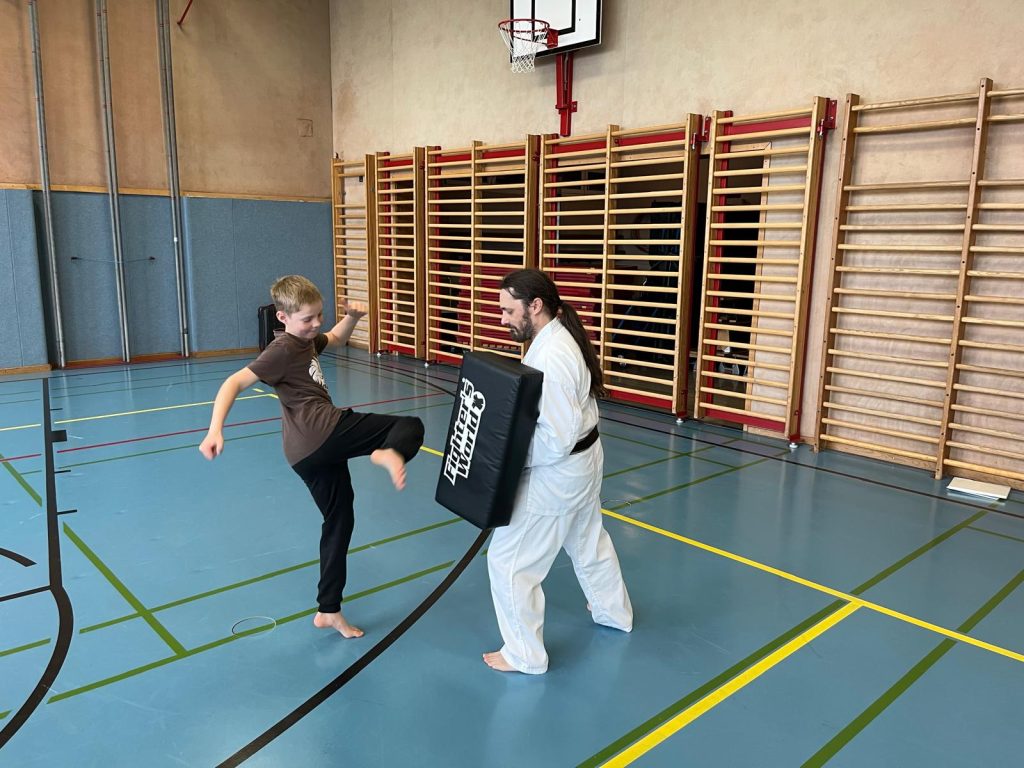 Schüler macht Fußstoß auf Schlagpolster